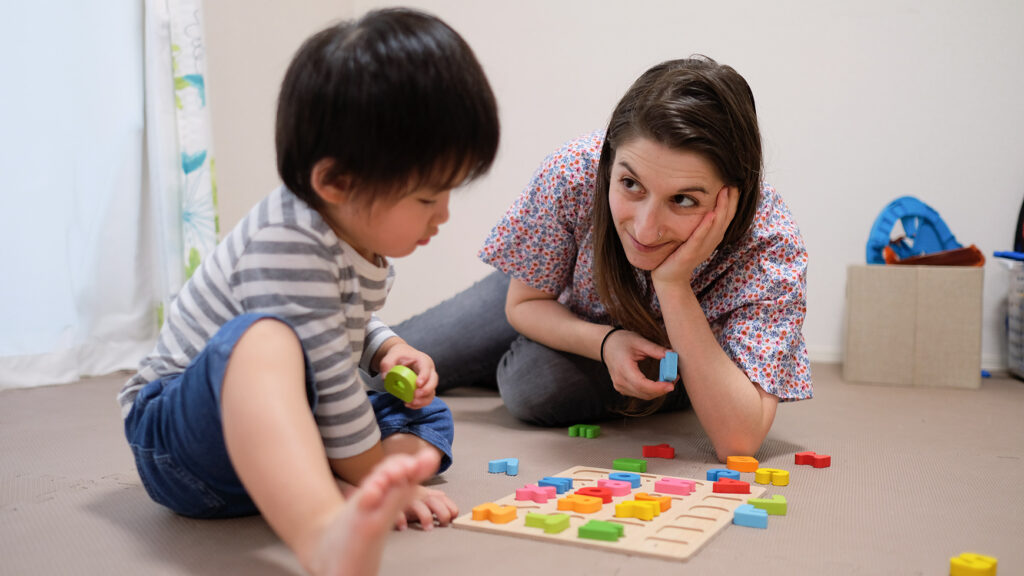 caucasian woman teaching english to asian toddler with alphabet blocks
